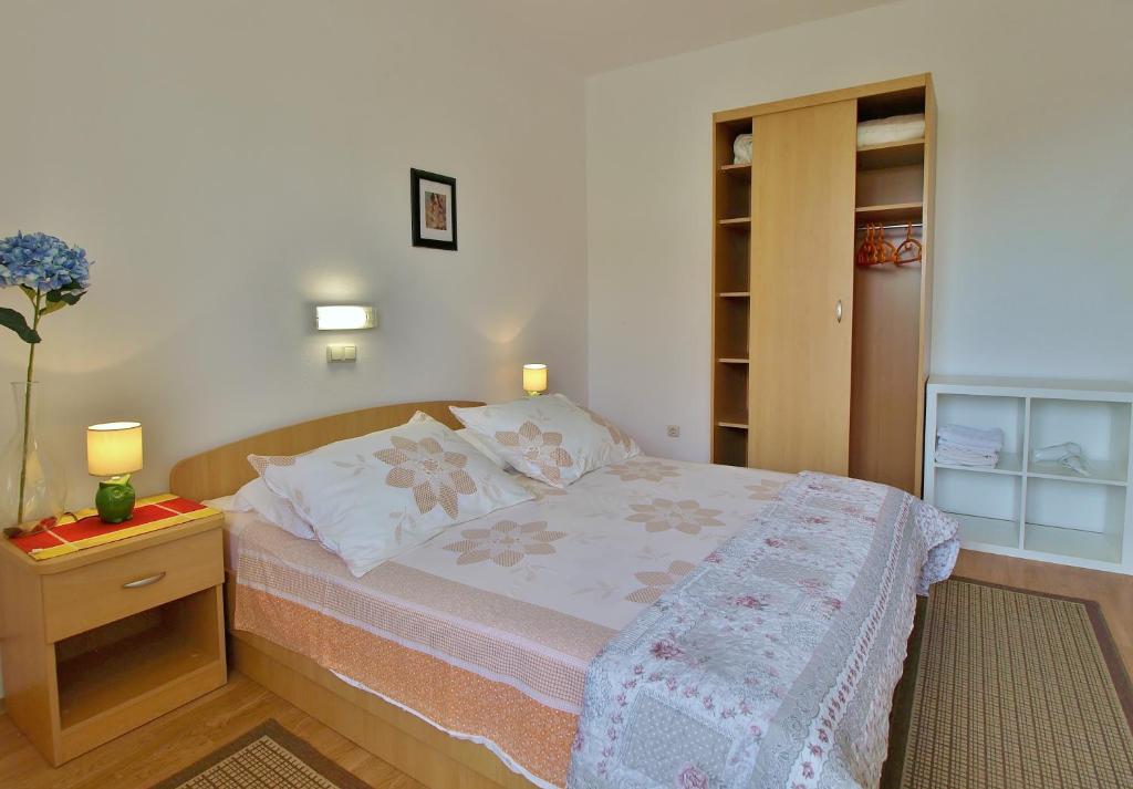 a small bedroom with a bed and a night stand at Apartments Eufemija in Rab