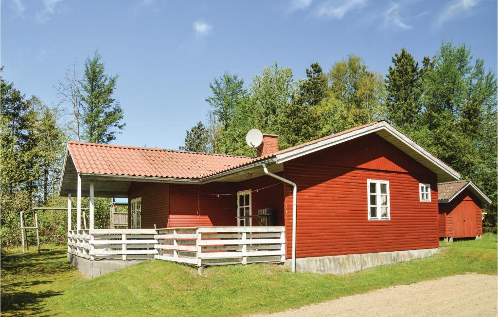 a red house with a white fence in the grass at Nice Home In Lgstr With Kitchen in Trend