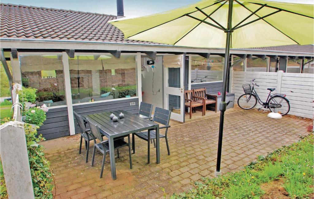 a patio with a table and a yellow umbrella at Golfparken in Danland Løjt