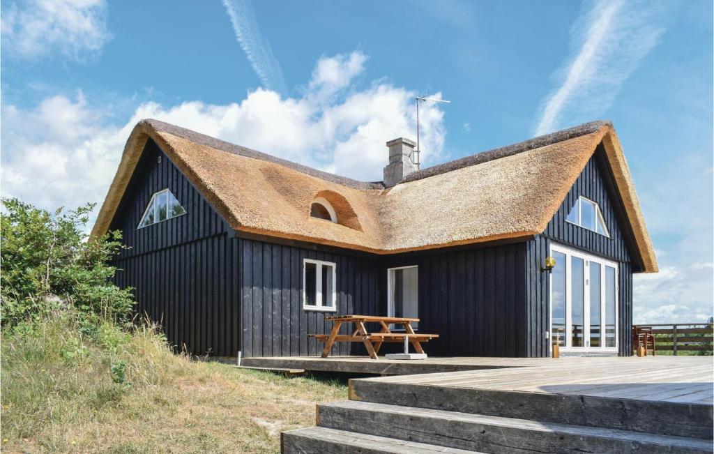 ein schwarzes Haus mit einem Strohdach in der Unterkunft Beautiful Home In Knebel With Kitchen in Knebel
