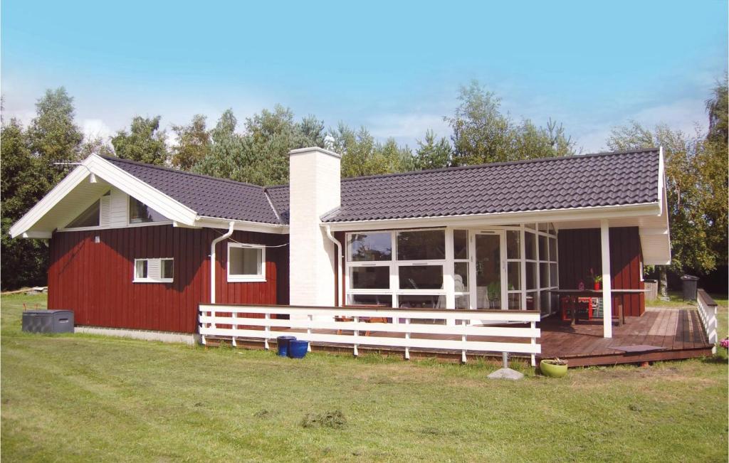 een klein rood-wit huis met een terras bij Cozy Home In Stege With Sauna in Stege