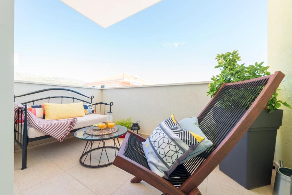 een balkon met een stoel, een tafel en een bank bij Narancin Apartments in Trogir