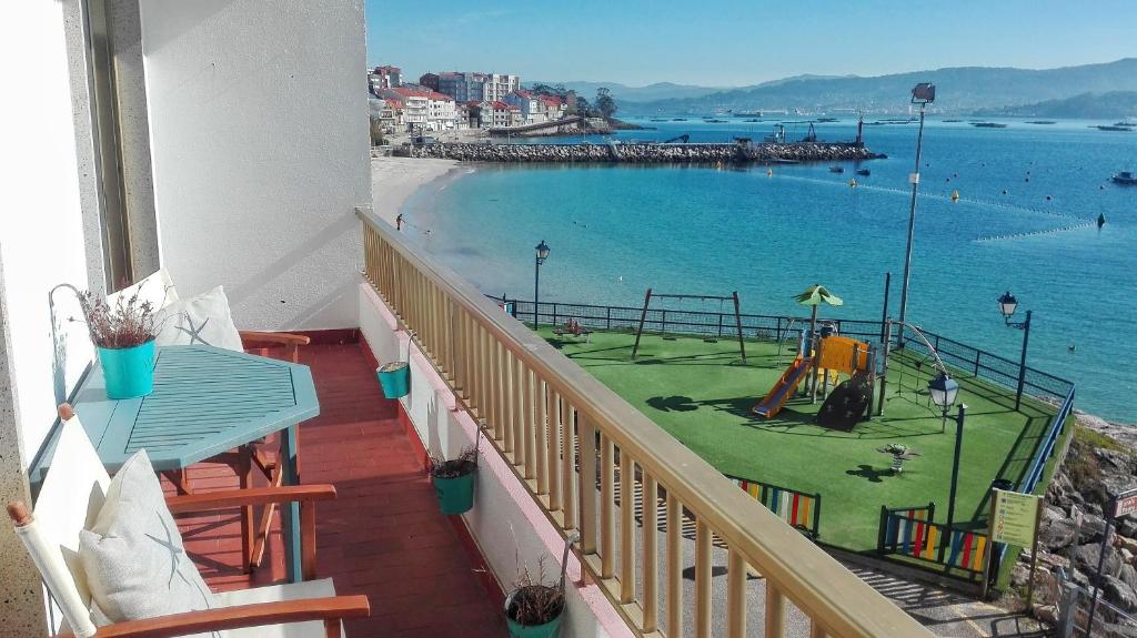 een balkon met uitzicht op de oceaan en een speeltuin bij Apartamento Rías Baixas - 1a Línea Playa Raxó in Raxo
