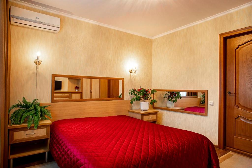 a bedroom with a red bed and two mirrors at Apartments at the Central Square in the City Center in Kherson