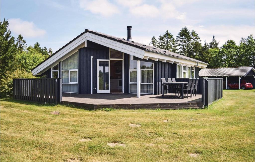 KrejbjergにあるBeautiful Home In Ejstrupholm With 3 Bedrooms And Wifiのデッキとテーブル付きの黒いコテージ