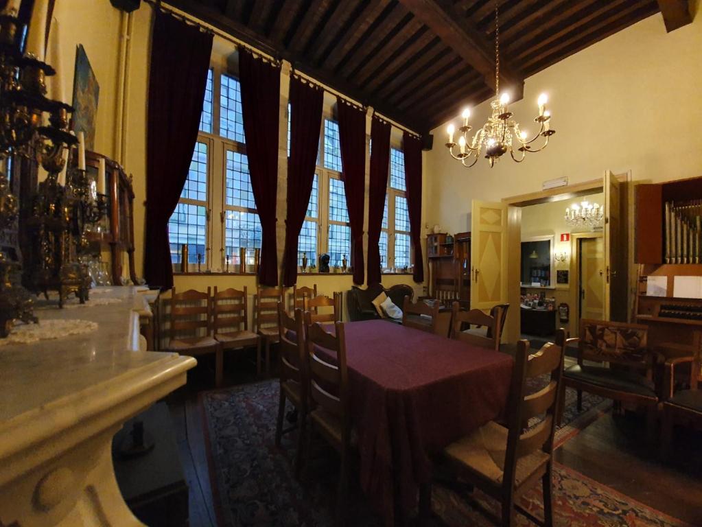 a dining room with a table and chairs and windows at Erasmus Hotel in Ghent