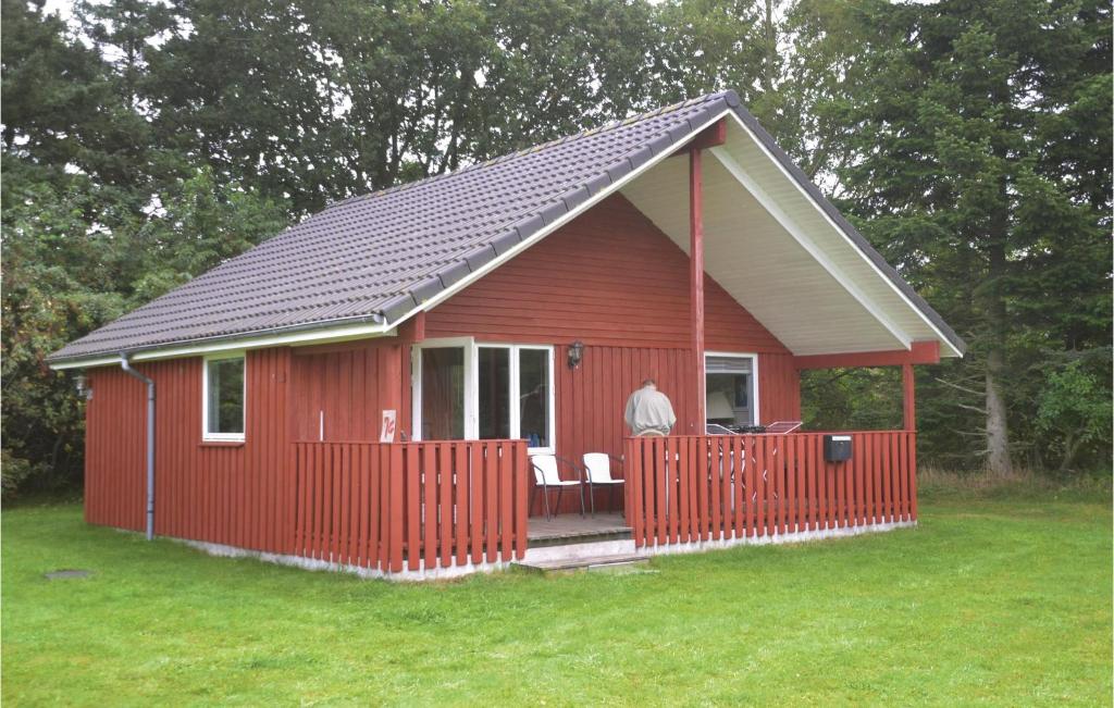 a red cabin with a red fence in the grass at 3 Bedroom Lovely Home In Tarm in Hoven