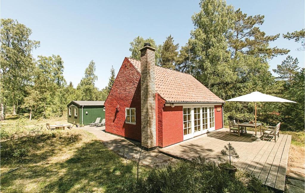 une maison rouge avec une table de pique-nique et un parasol dans l'établissement Finkereden, à Bedegård