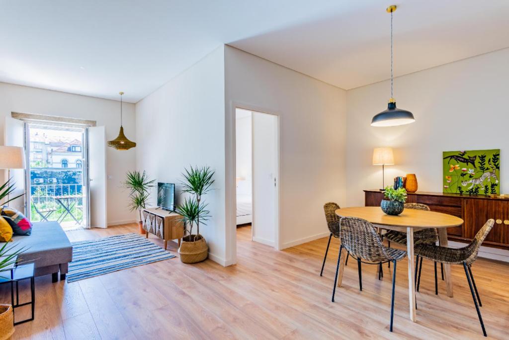 een woonkamer met een tafel, stoelen en een bank bij Boavista Garden Apartment in Porto