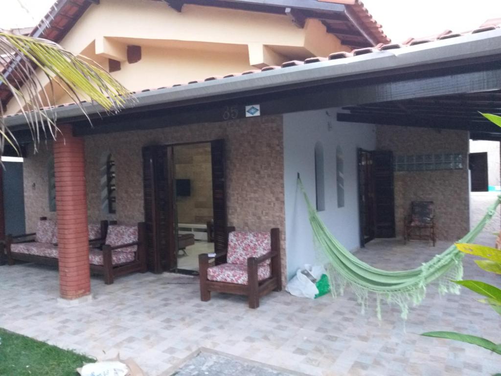 een patio van een huis met 2 stoelen en een hangmat bij Casa em Condominio Caragua in Caraguatatuba