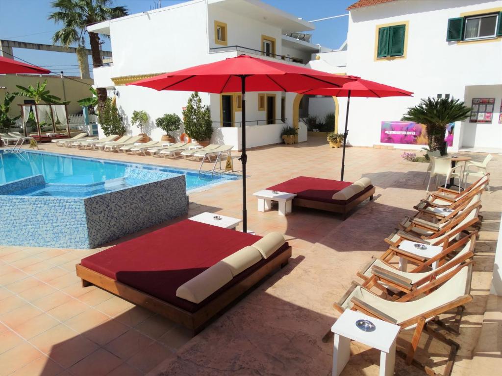 a pool with chairs and umbrellas next to a building at Oasis Beach Club in Kavos