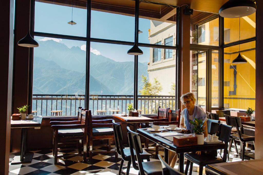 a person sitting at a table in a restaurant with a view at Mountain View Station in Sa Pa