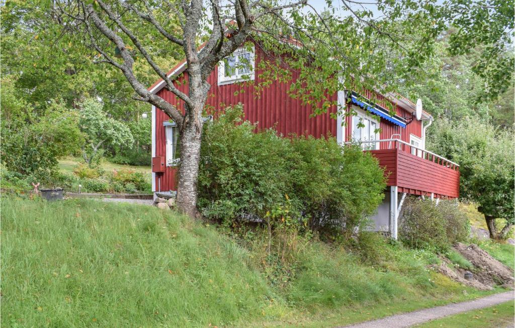 a red house with a tree in front of it at Nice Home In Gamleby With House A Panoramic View in Gamleby
