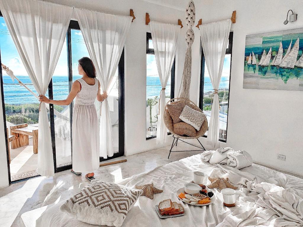 a woman standing in a bedroom looking out at the ocean at Icaco Island Village - Adults Only in Isla Mujeres