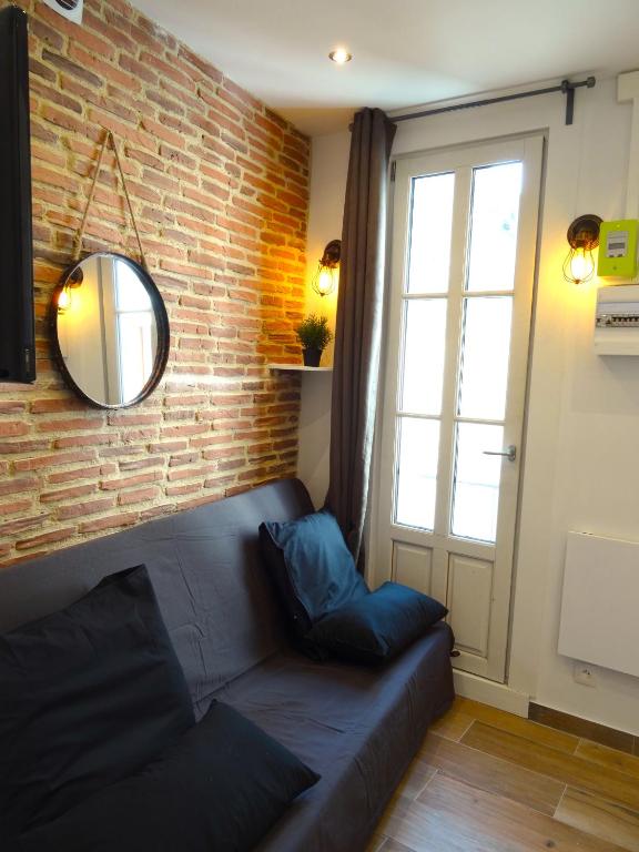 un salon avec un canapé et un mur de briques dans l'établissement ★★★Studio Heart of Le Marais, Design Flat★★★, à Paris
