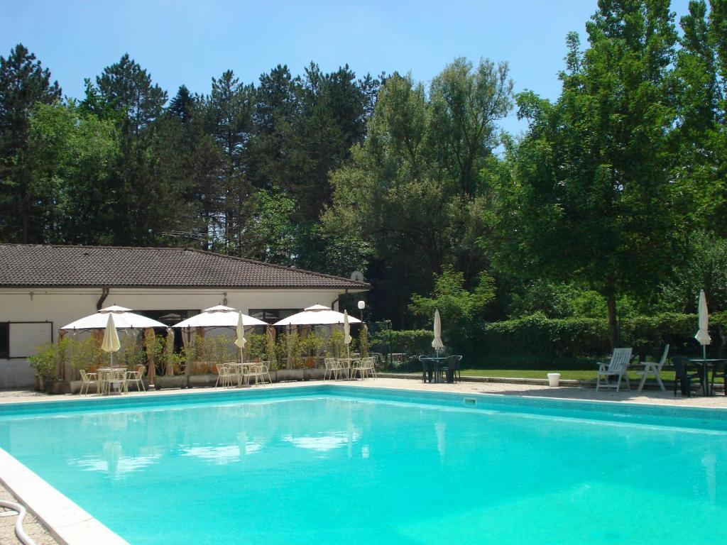 a swimming pool with umbrellas and tables and chairs at Rio Verde camping villaggio in Costacciaro