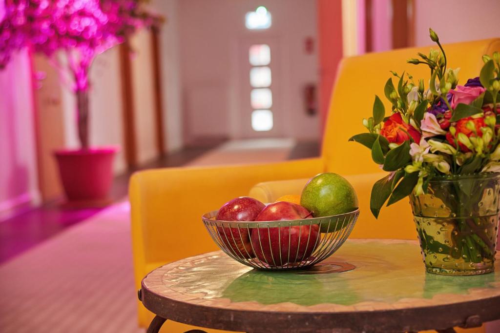 un bol de fruta y un jarrón de flores sobre una mesa en Joos Hotel en Bergheim