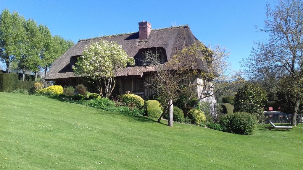 uma casa velha numa colina verde com um quintal em Haras de la Valterie em Saint-Hymer