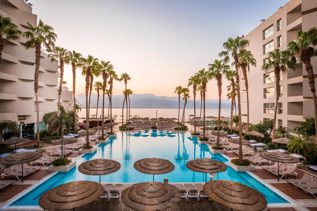 a hotel pool with chairs and palm trees at Aria in Eilat