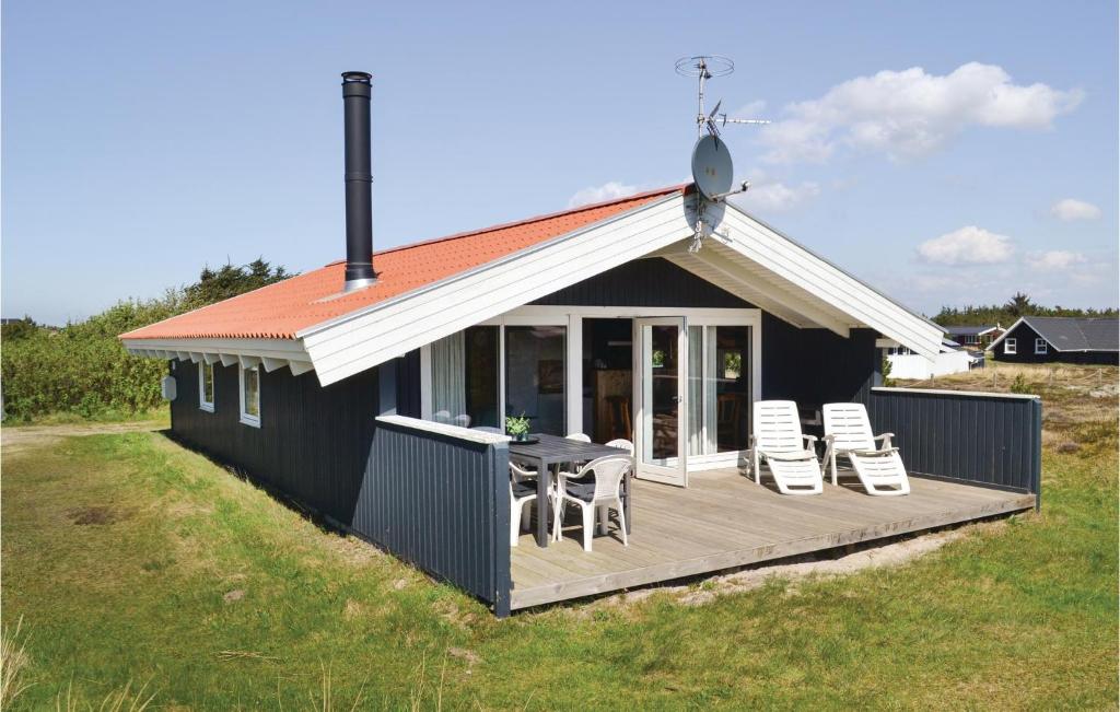 BjerregårdにあるAmazing Home In Hvide Sande With 3 Bedrooms And Wifiのデッキ(椅子、テーブル付)が備わる家