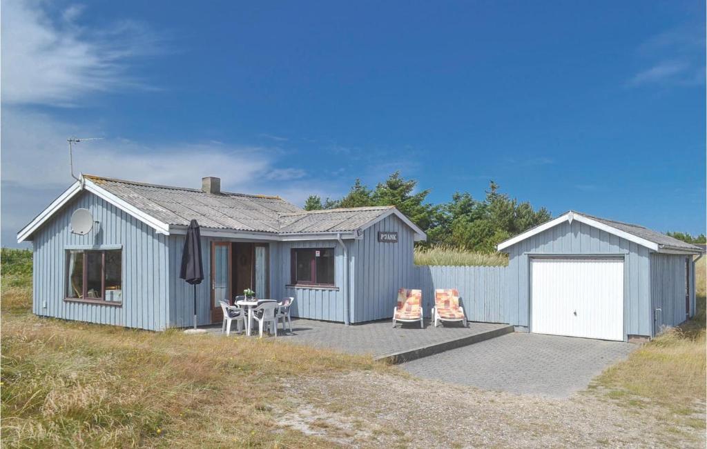 a blue house with a table and two chairs at Holiday Home Arvidvej Denmk Xii in Bjerregård