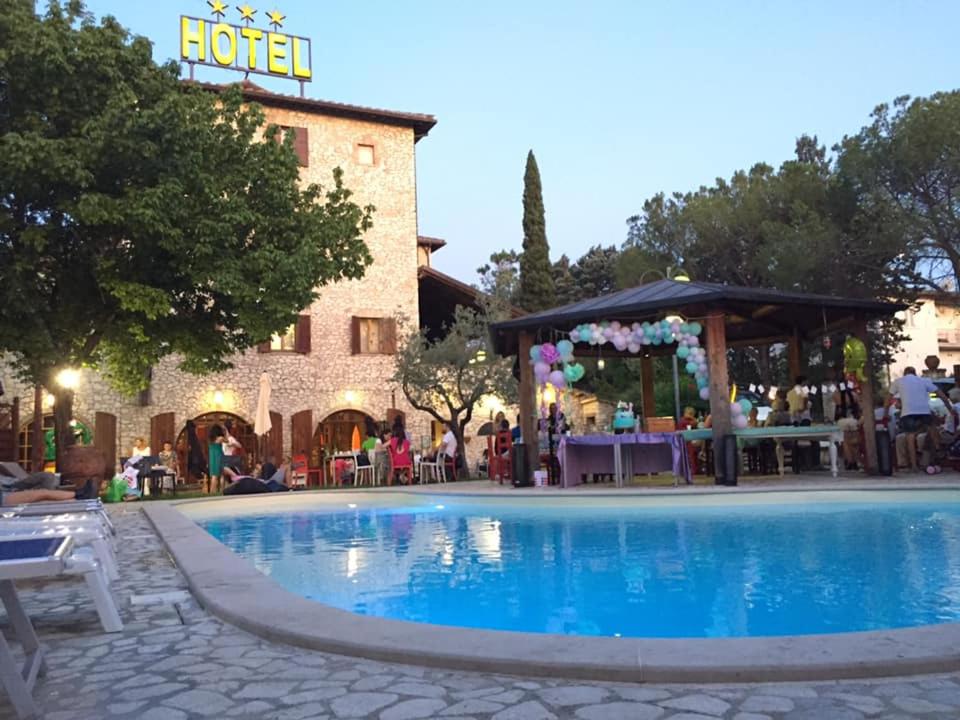 a hotel with a swimming pool in front of a building at Hotel Benedetti in Campello sul Clitunno