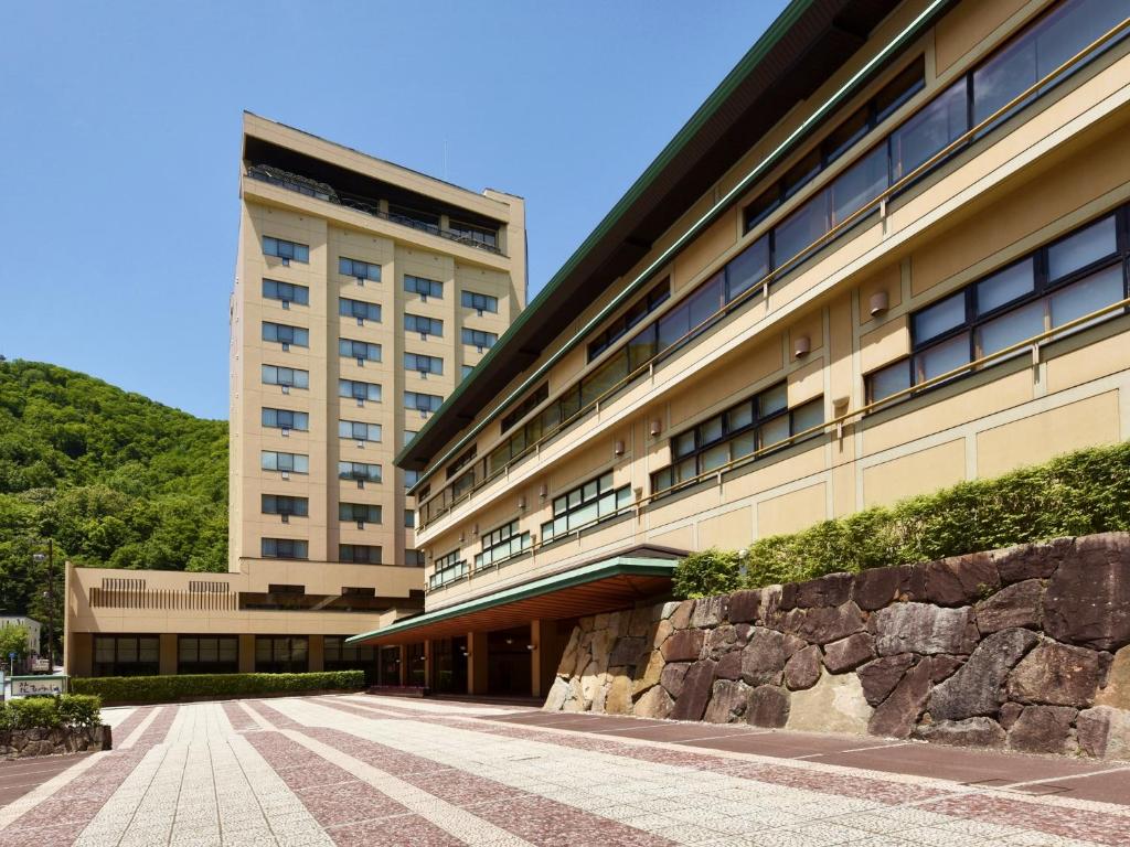 um grande edifício com uma parede de pedra em frente em Hanamomiji em Jozankei