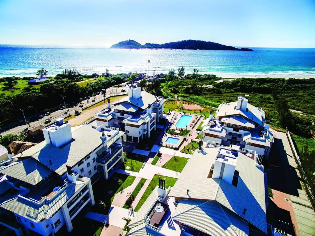 una vista aérea de un edificio con el océano en el fondo en Condominio Villas do Campeche, en Florianópolis