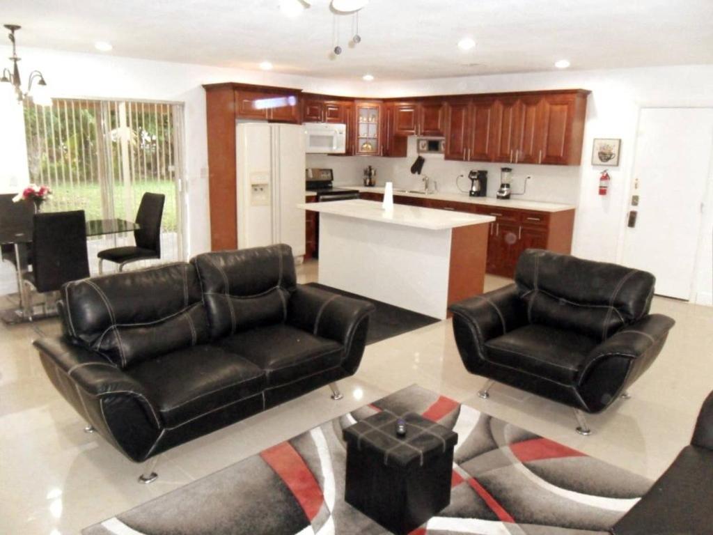ein Wohnzimmer mit schwarzen Ledermöbeln und eine Küche in der Unterkunft The Jazzy Escape in Miami