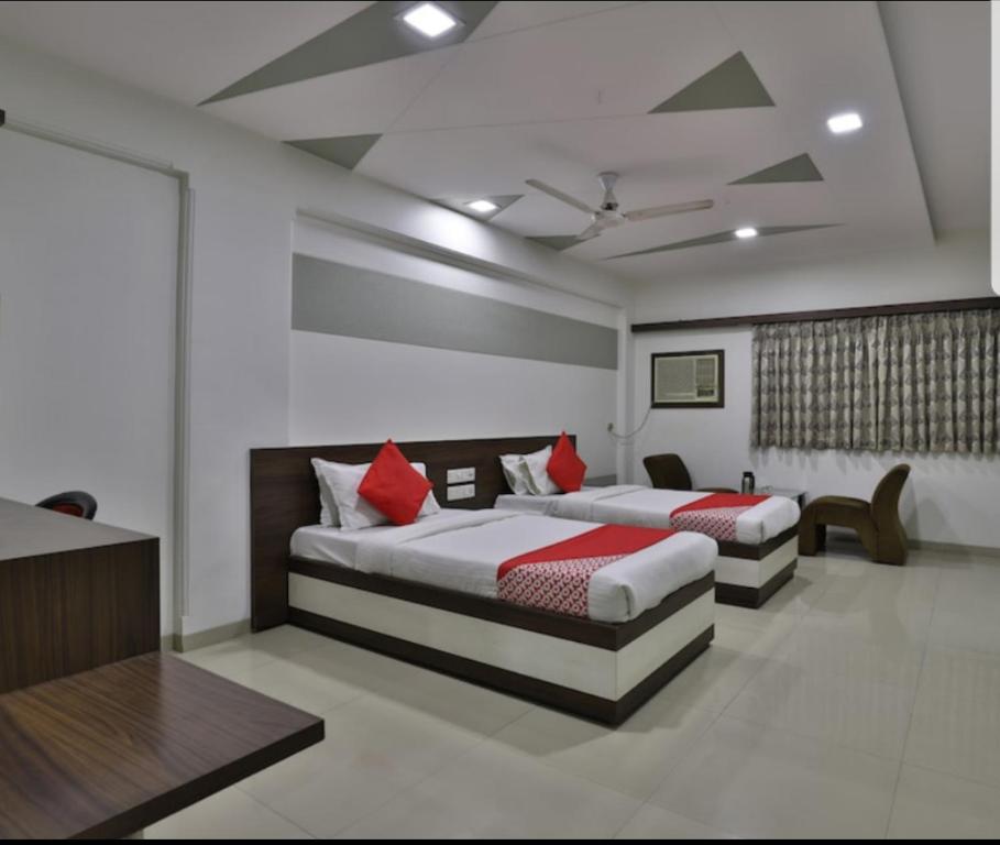 two beds with red pillows in a room at HOTEL OSTRIA in Surat