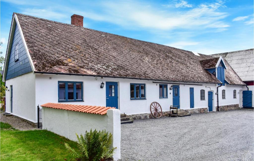 ein weißes Gebäude mit blauen Fenstern und einem Dach in der Unterkunft Amazing Home In Ystad With Kitchen in Ystad