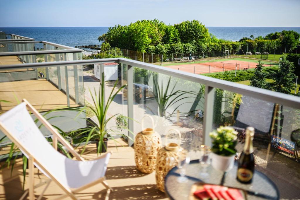 einen Balkon mit einem Tisch und Stühlen sowie einen Tennisplatz in der Unterkunft Apartament GOLD Gardenia Dziwnów in Dziwnów