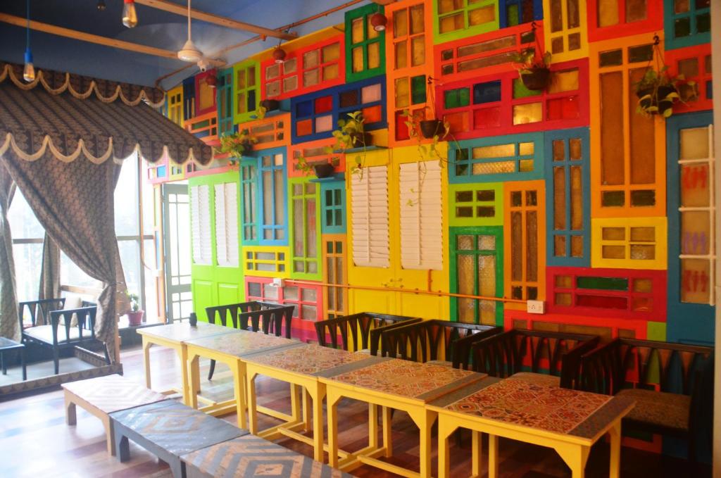 um quarto com uma parede colorida com mesas e cadeiras em Salaam Namastey Backpackers em Mumbai