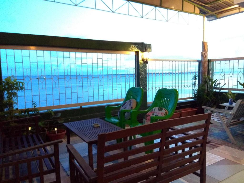 een patio met stoelen en een tafel en uitzicht op het water bij Sandakan Backpackers Hostel in Sandakan