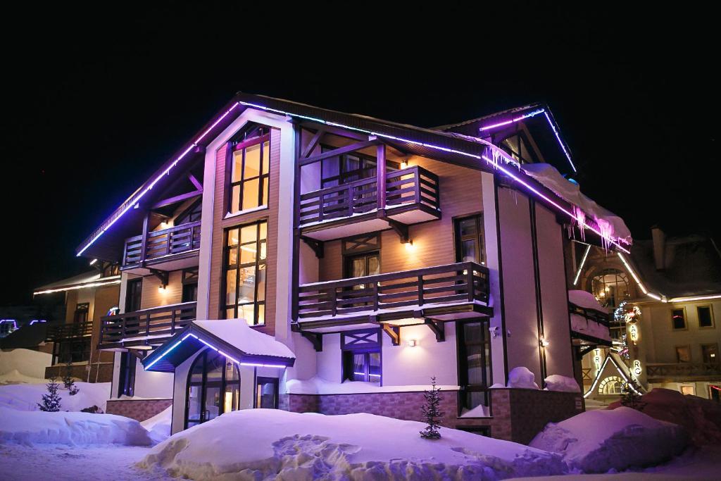 a house with purple lights on it in the snow at Alpen Club in Sheregesh