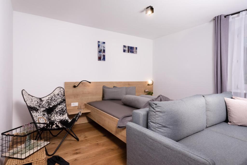 ein Wohnzimmer mit einem Sofa und einem Stuhl in der Unterkunft Apartment Macho in Innsbruck