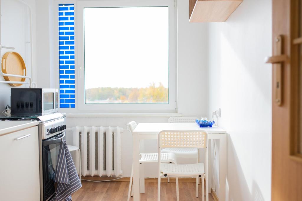 a kitchen with a table and chairs and a window at Centro apartamentai in Naujoji Akmenė