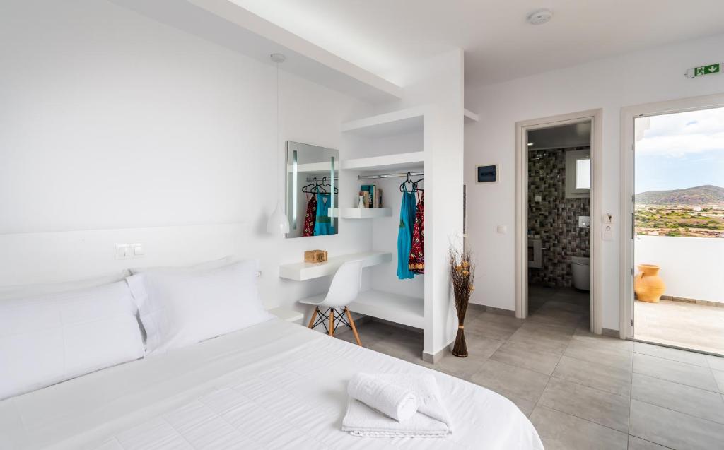a white bedroom with a white bed and a desk at Orizontes Boutique Studios in Adamantas