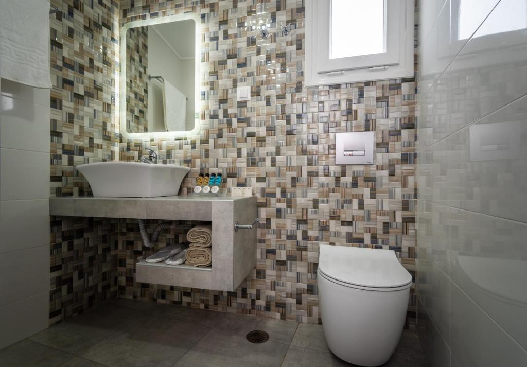 a bathroom with a sink and a toilet and a mirror at Orizontes Boutique Studios in Adamantas