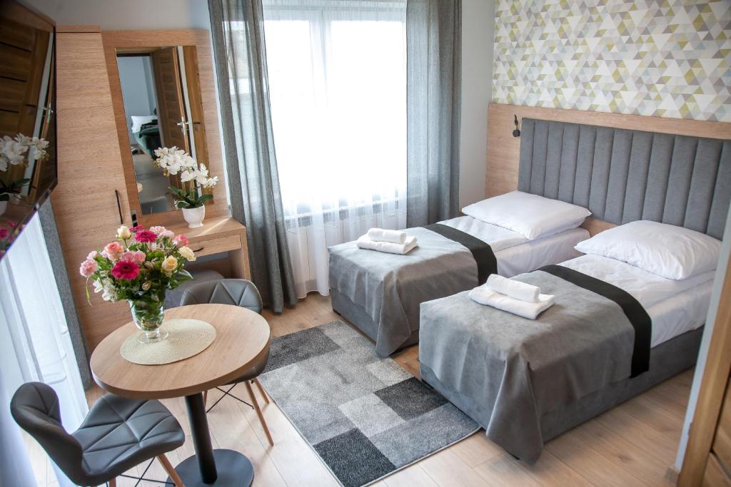 a hotel room with two beds and a table with flowers at Willa-Wita in Kalwaria Zebrzydowska