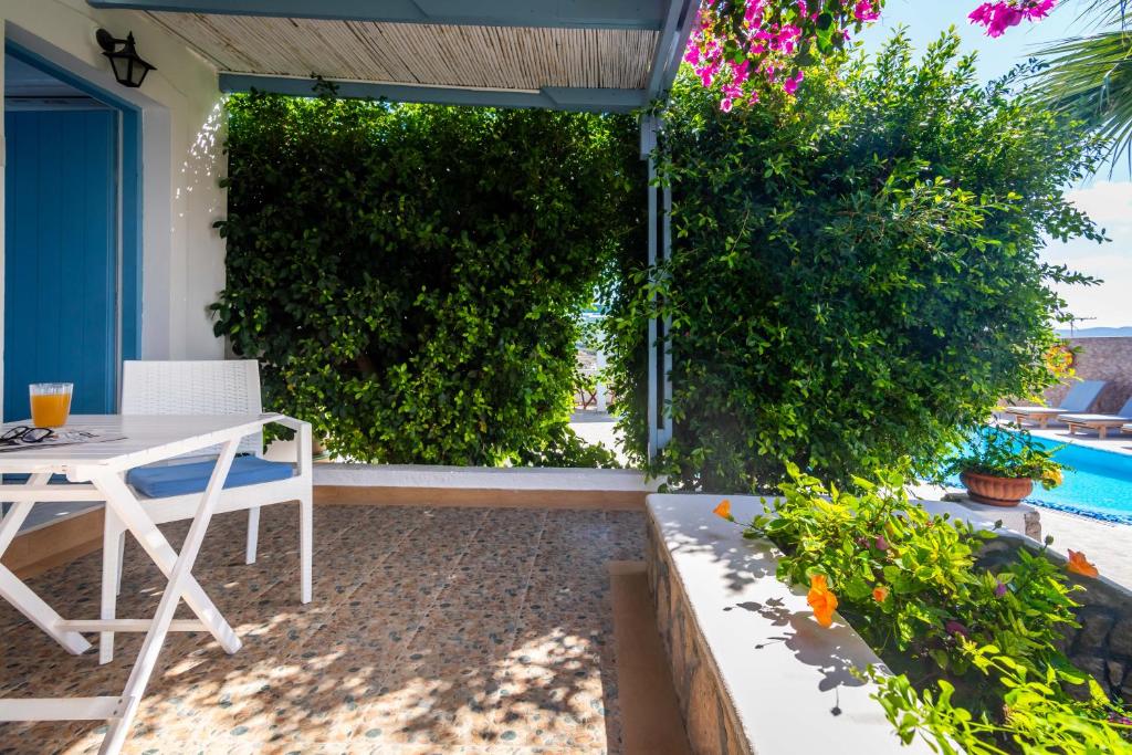 a patio with a white table and chairs and a hedge at Orizontes Boutique Studios in Adamantas