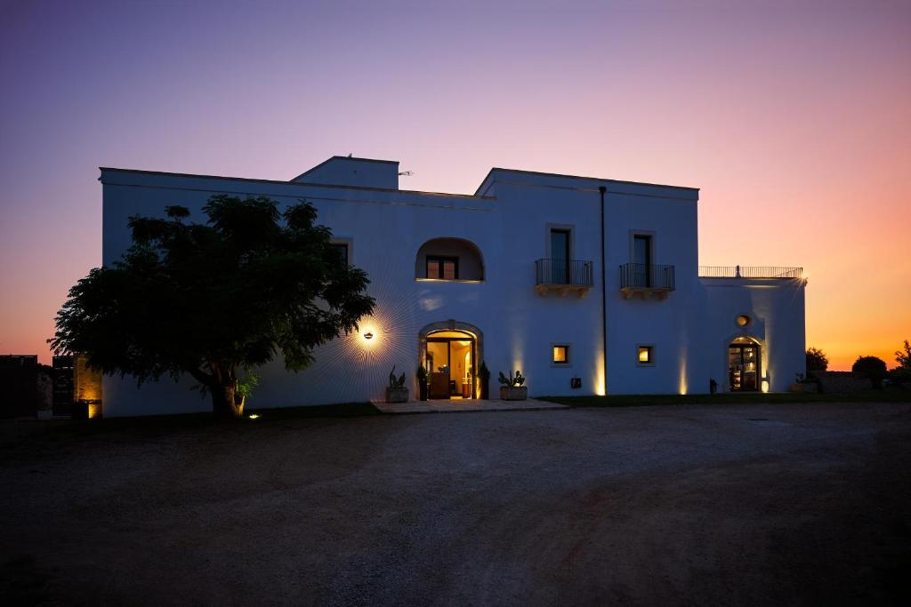 a large white building with a sunset in the background at Masseria Bagnara Resort & Spa in Marina di Lizzano