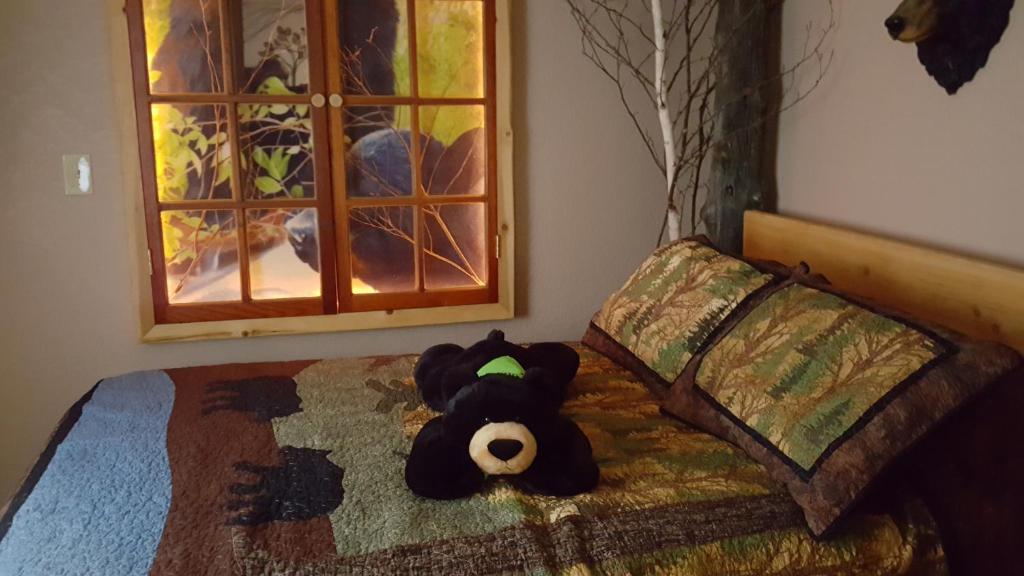 a teddy bear laying on a bed in a bedroom at Bear Cove Inn in Saint Ignace