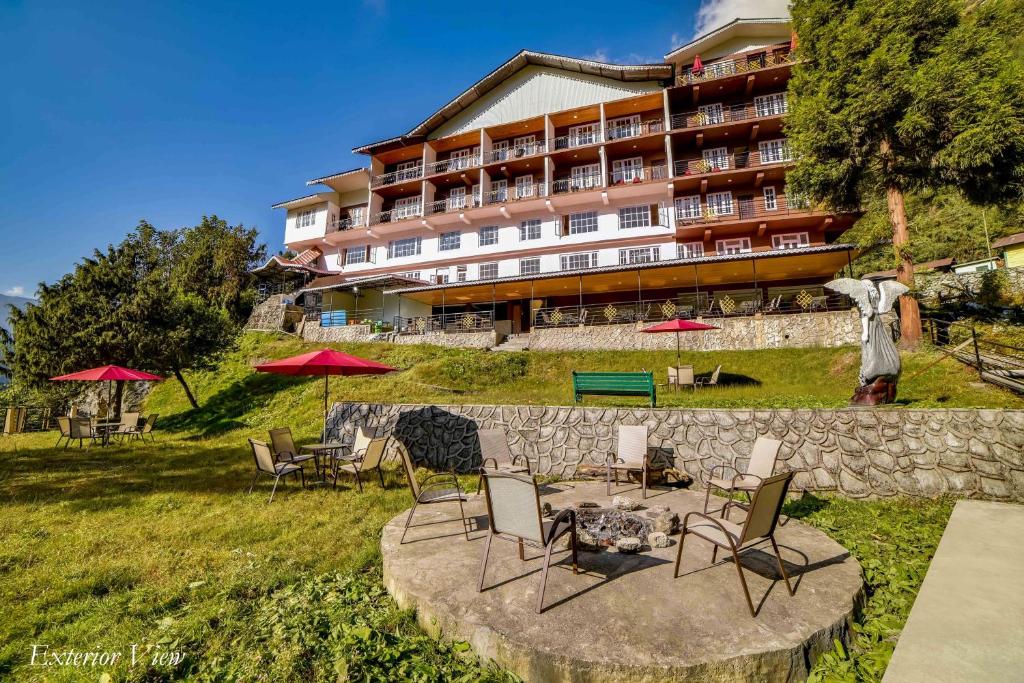 a hotel with chairs and tables in front of a building at Summit Khangri Karpo Retreat & Spa in Lachung