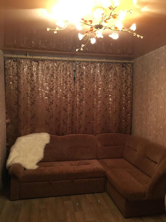 sala de estar con sofá marrón y lámpara de araña en Apartments at Laureatov 43 en Norilsk