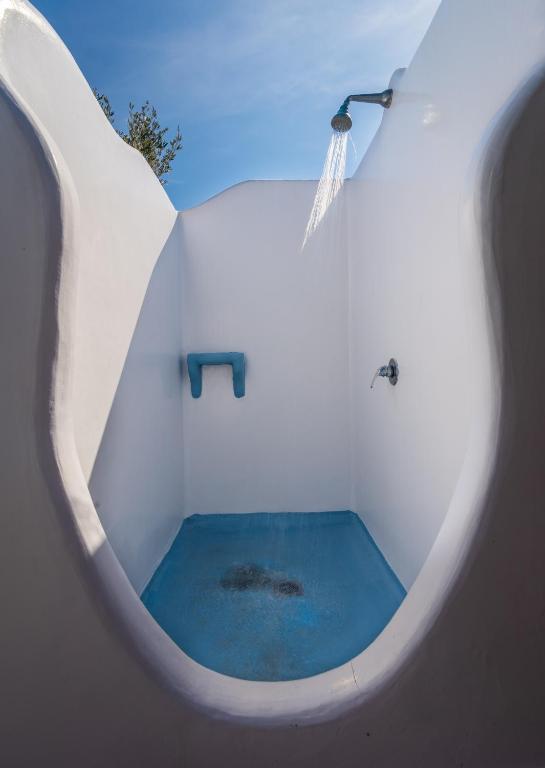 a white bathroom with a tub with a blue pond at Orizontes Boutique Studios in Adamantas