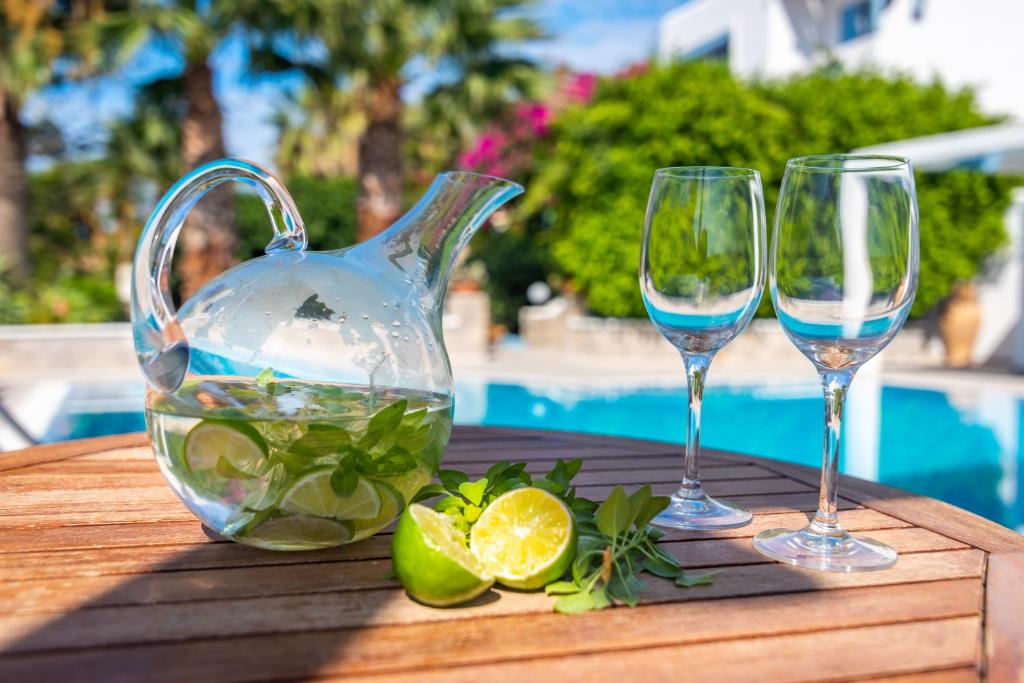 two wine glasses and a pitcher of water on a table at Orizontes Boutique Studios in Adamantas