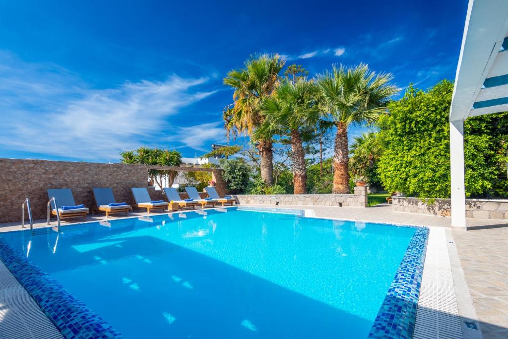 a swimming pool with chairs and palm trees at Orizontes Studios in Adamantas