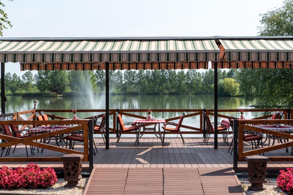 a patio with tables and chairs next to a lake at Hotel Bíbic és Tüskevár Étterem és Horgásztó in Nyíregyháza