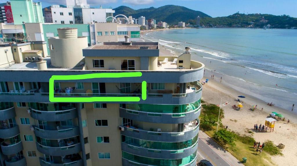 a building with a green arrow on it next to a beach at 2 Dormitórios Vista Mar in Itapema